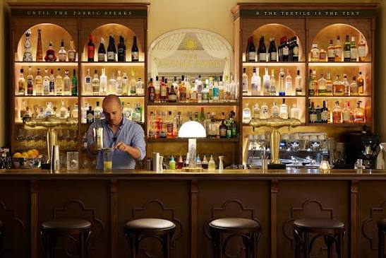The bar at The Arding Room, lit shelves behind a wooden counter
