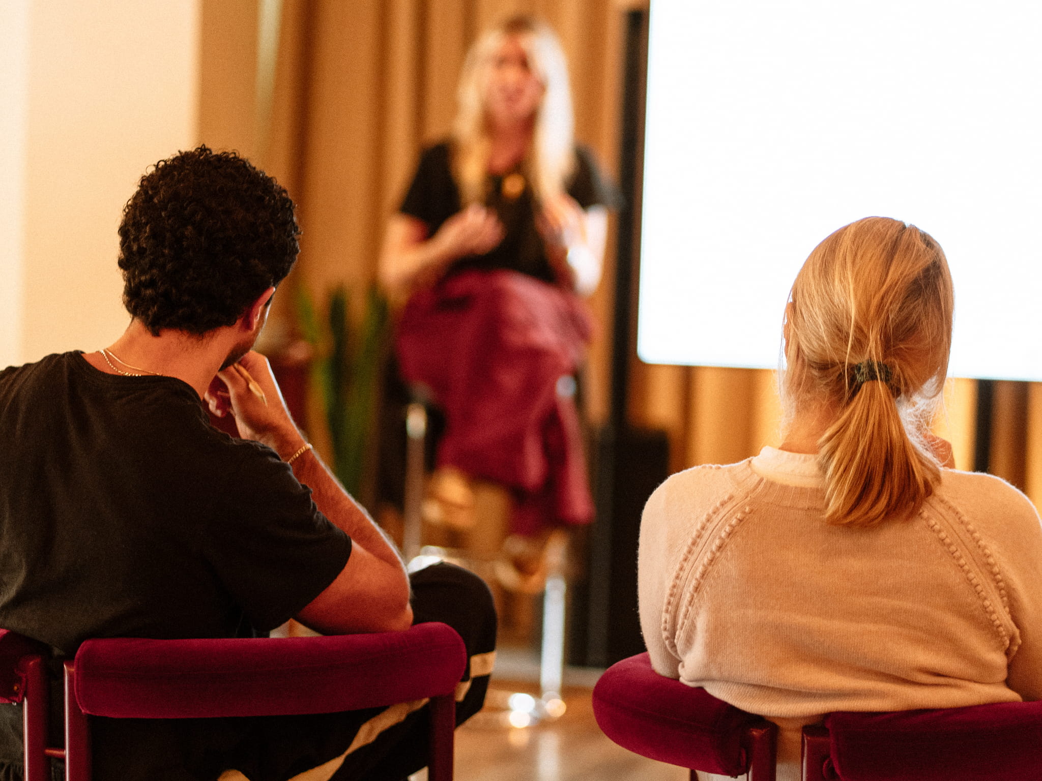 Two guests listening as Emmy speaks to the room
