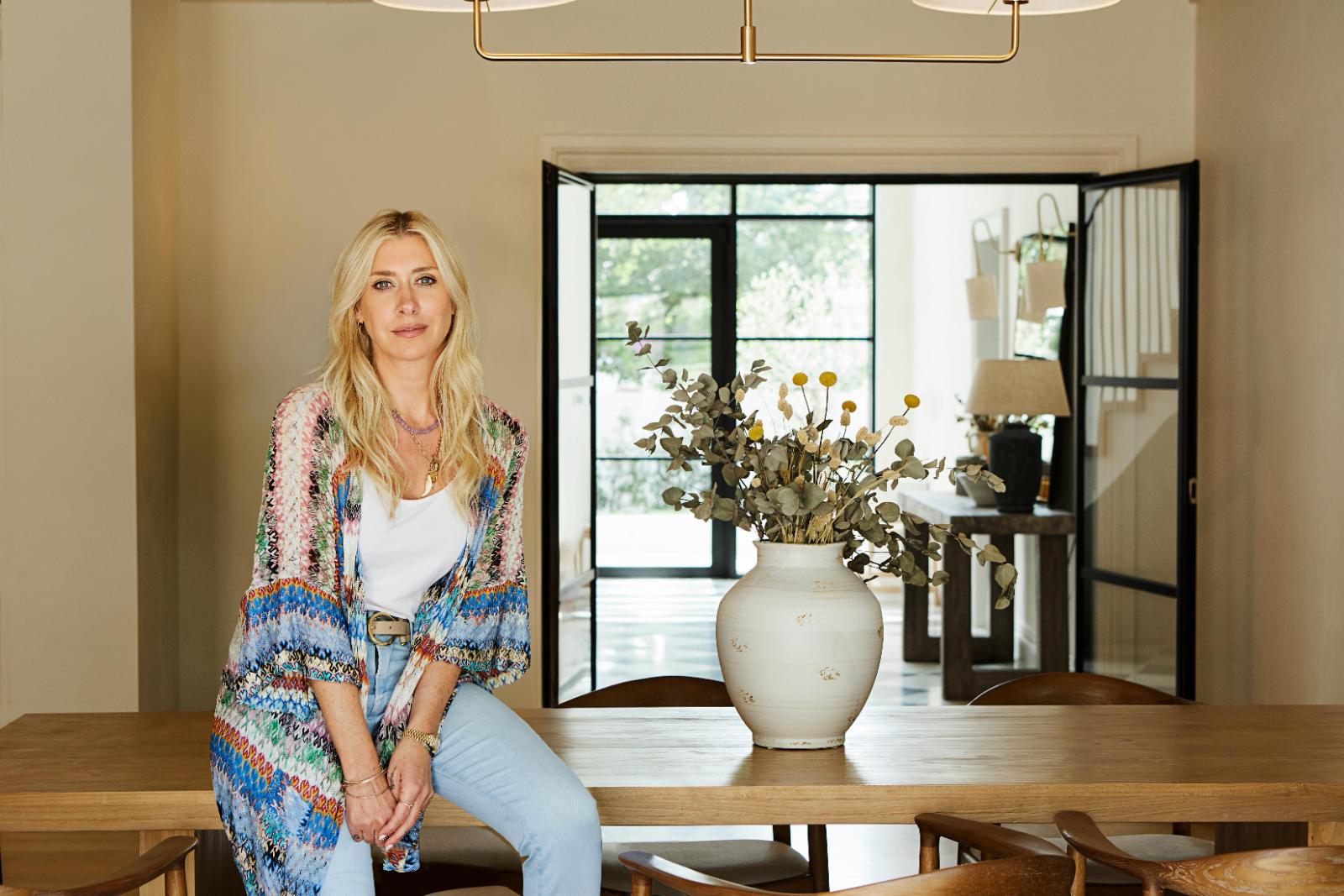 Emmy Brunner sitting on a dining table beside a vase of dried eucalyptus